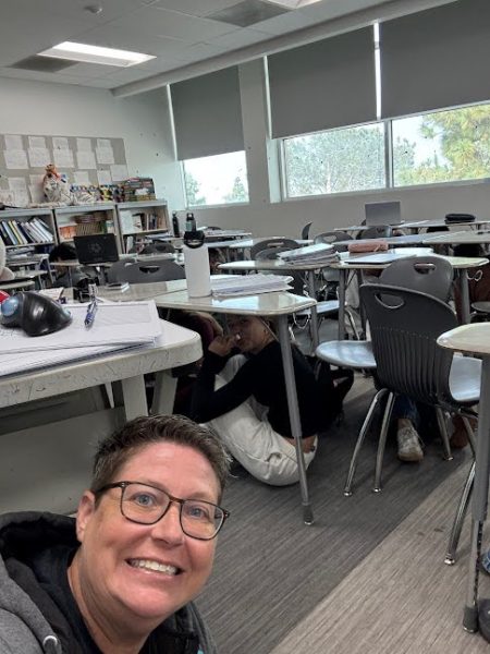 Latin teacher Wendy Wira poses under the desk during the Lockdown. Image via Wendy Wira.