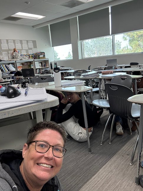 Latin teacher Wendy Wira poses under the desk during the Lockdown. Image via Wendy Wira.
